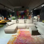 Divano modulare PIX beige con penisola e pouf, vista frontale in showroom